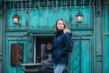 Beautiful happy young woman with a cup of coffee in a winter coat with a knitted fashionable...