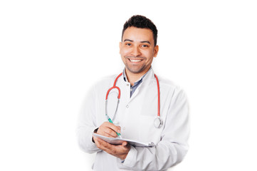 Doctor with stethoscope around his neck looking at the camera and writing recipe