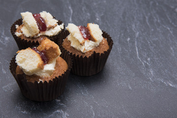 Three raspberry and cream cupcakes on a dark marble background with copy space 