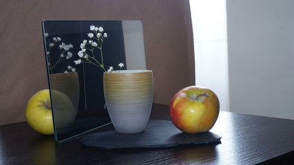 still life with a mirror and fruit on a glossy dark surface with counterlighting