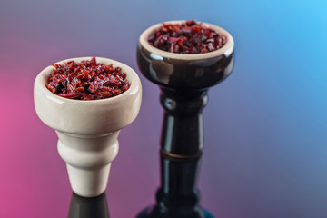 shisha with Apple flavor in glossy white and black bowls on a dark mirror surface with colored reflections, prepared for Smoking