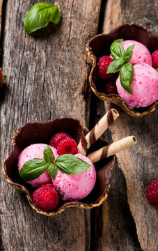 Ice cream, raspberry ice cream scoop in cone on wooden table. 