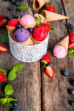 Ice cream, Strawberry and blueberry ice cream scoop in cone on wooden table. 