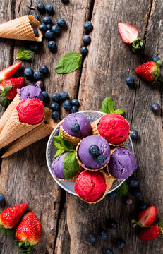 Ice cream, Strawberry and blueberry ice cream scoop in cone on wooden table. 