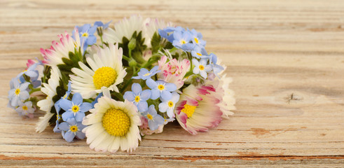 Obraz na płótnie Canvas Meadow flowers chamomile or daisies and forget me not closed up on old desk
