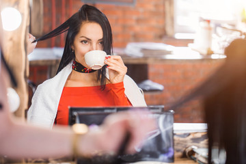 Beautiful young brunette woman at the makeup artist or hairdresser near the mirror.