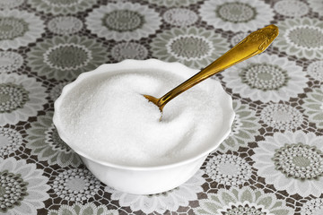 Yellow teaspoon in a sugar bowl on a kitchen table close-up.
