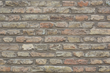 Wall made from red and sometimes colorful bricks of regular shapes and random distribution slotting...