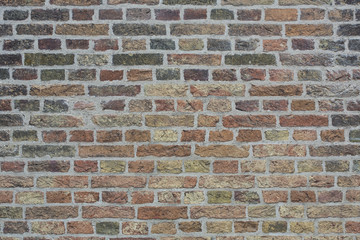 Wall made from red and sometimes colorful bricks of regular shapes and random distribution slotting together precisely. Close up architecture photography. Creative wallpaper photography.