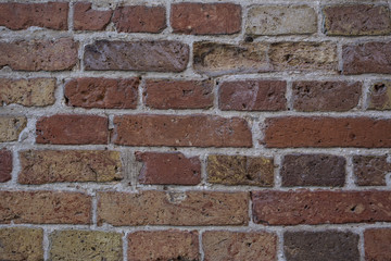 Wall made from red and sometimes colorful bricks of regular shapes and random distribution slotting together precisely. Close up architecture photography. Creative wallpaper photography.