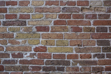 Wall made from red and sometimes colorful bricks of regular shapes and random distribution slotting together precisely. Close up architecture photography. Creative wallpaper photography.