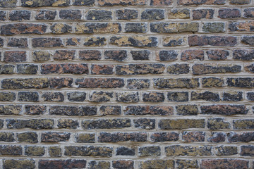 Wall made from red, black and sometimes colorful bricks of regular shapes and random distribution...