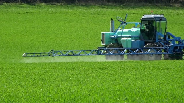Agriculture fertilizer working on farming field, agriculture machinery working on cultivated field and spraying pesticide