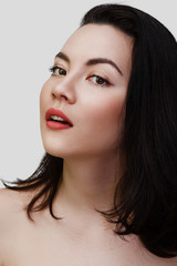 Young sexy lady with clean skin red lips and black straight hairstyle. Mixed race Caucasian Asian female model isolated on gray background