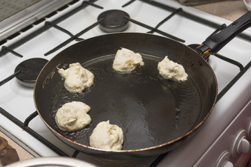 Dough pieces in boiling oil in a frying pan, cooking fritters