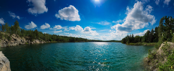 Beautiful summer quarry lake in the cliffs with cloudy blue sky, natural landscape background