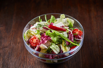 Fresh vegetable salad and ripe veggies on cutting board over wooden background, close up, selective focus