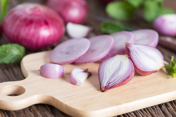 Sliced of red onion on wood board.