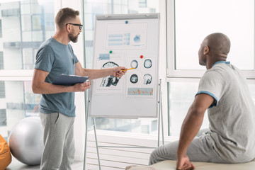 Obraz premium Human anatomy. Nice smart doctor showing his patient the picture while explaining human anatomy