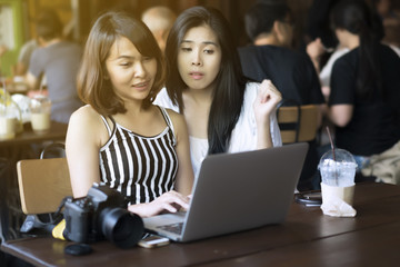 two women using laptop computer searching on internet.