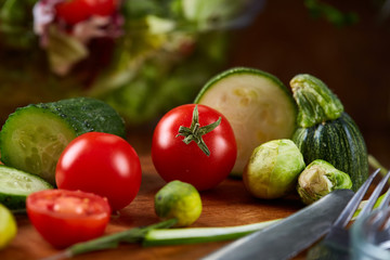 Fresh vegetable salad and ripe veggies on cutting board over wooden background, close up, selective focus