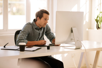 Naklejka na ściany i meble Man using a digitizer to write text in computer