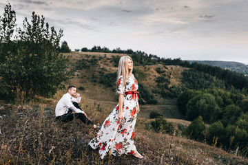 Fototapeta premium Portrait of a beautiful girl. A loving couple against the background of the mountains at sunset.