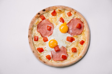 Breakfast pizza with fried eggs and ham isolated on white. Top view