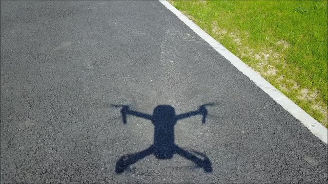 L'ombre d'un drone sur le bitume qui vole au raz du sol