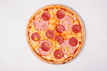 Pizza with salami, ham and corn isolated on white. Top view