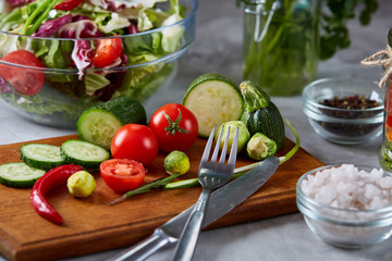 Fresh vegetable salad and ripe veggies on cutting board over white background, close up, selective focus