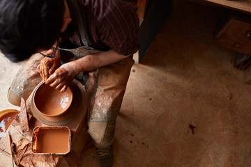 Portrait of a male potter in apron molds bowl from clay, selective focus, close-up