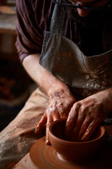 Portrait of a male potter in apron molds bowl from clay, selective focus, close-up