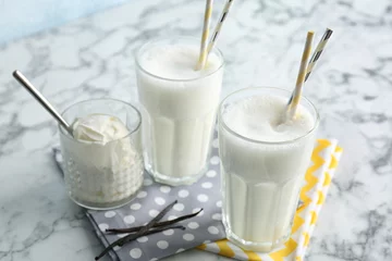 Poster Glasses with milk shake and tasty vanilla ice cream on light background © New Africa