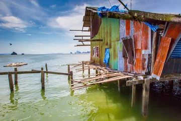 Foto op Plexiglas A shack on stilts in the water. Dwelling on the water. Poverty. Houses on the water in Thailand. © Grispb