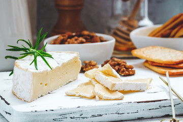 Cheese plate served with crackers, honey and nuts. Camembert on white wood serving board over white texture background. Appetizer theme. - obrazy, fototapety, plakaty