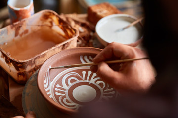 Scary face alike handmade potter mug on a wooden shelf, close-up, shellow depth of field.