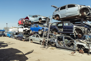 Car bodies waiting recycling/Piles of used cars disassembled in a cemetery yard car recycling center with a ladder and car shadows .