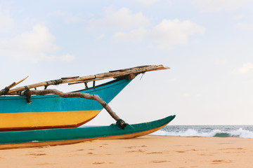 Obraz premium Close-up Sri-Lanka fishing boat on the ocean Narigama beach. Traditional blue-yellow wooden painted ship.