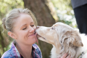 A woman being licked on the face by her dog - obrazy, fototapety, plakaty