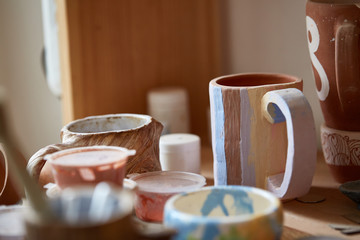 Close-up of various paint mugs and brushes in holder on worktop, selective focus, side view.