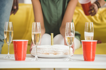 Champagne and birthday cake on table in front of people at party