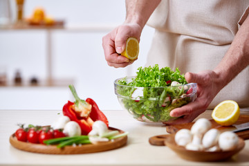 Obraz na płótnie Canvas Man cooking at kitchen making healthy vegetable salad, close-up, selective focus.