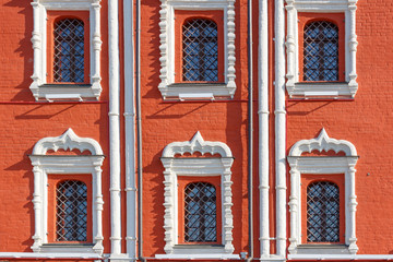 Fototapeta na wymiar Windows with decorative metal grilles on the facade of red brick of ancient house closeup