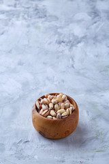 Almonds in brown bowl on white textured background, top view, selective focus.