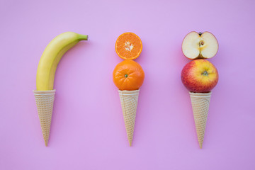 Fresh fruit orange, tangerine, apple in ice cream on pink background