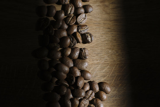Dark Roasted Coffee Beans on Wooden Background with Dramatic Light