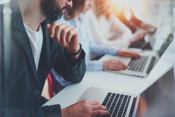 Closeup view of young Coworkers working together on new business presentation at sunny meeting room.Horizontal.Blurred background.Cropped.