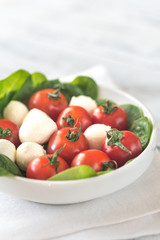Fresh cherry tomatoes with mozzarella and spinach leaves