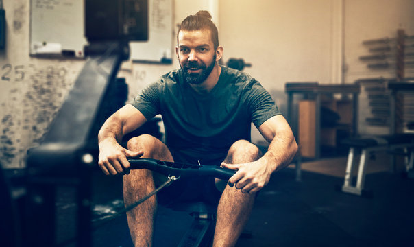 Smiling young man working out on a gym rowing machine